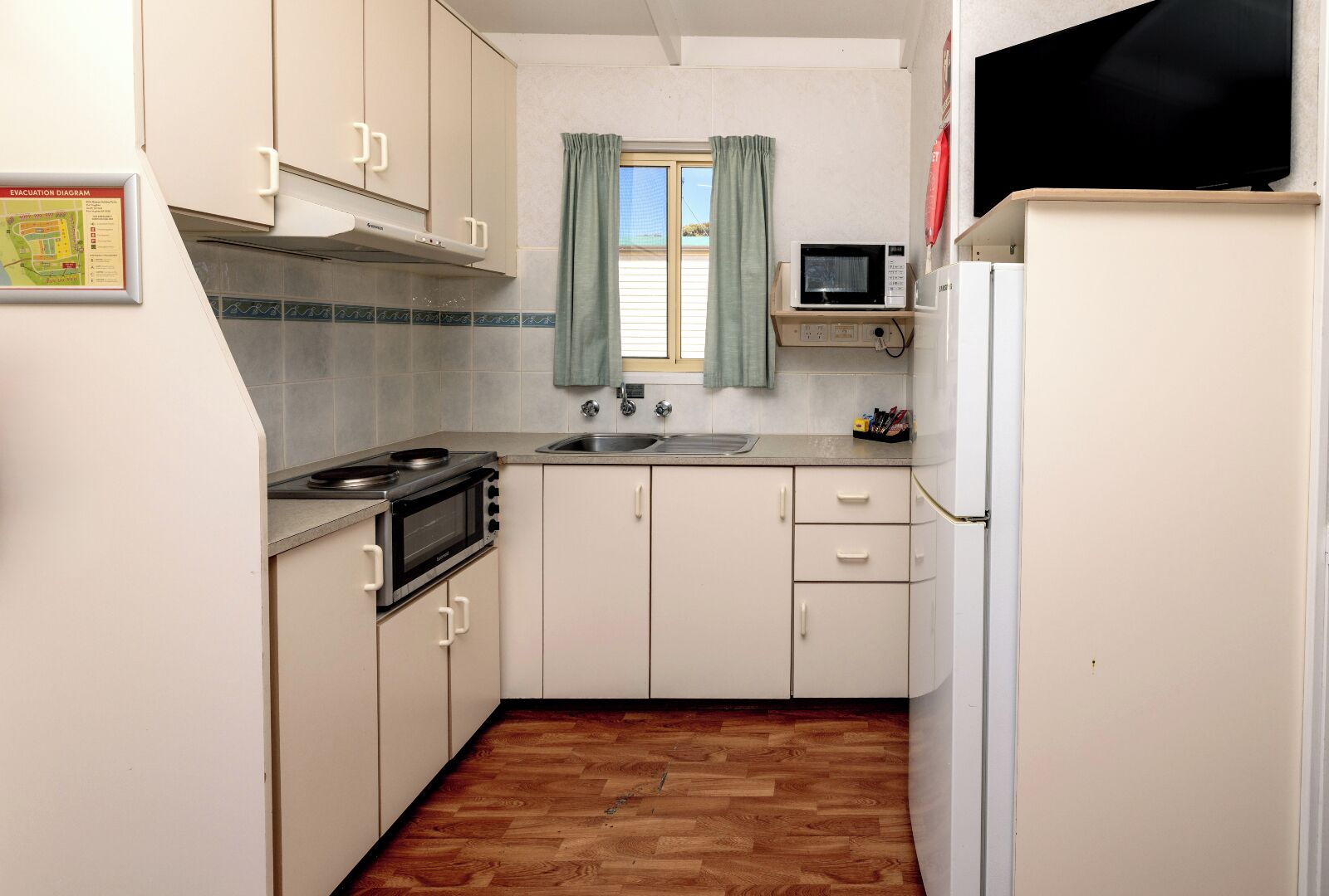 Eine kleine Küche mit Herd, Mikrowelle, Spüle und Kühlschrank.