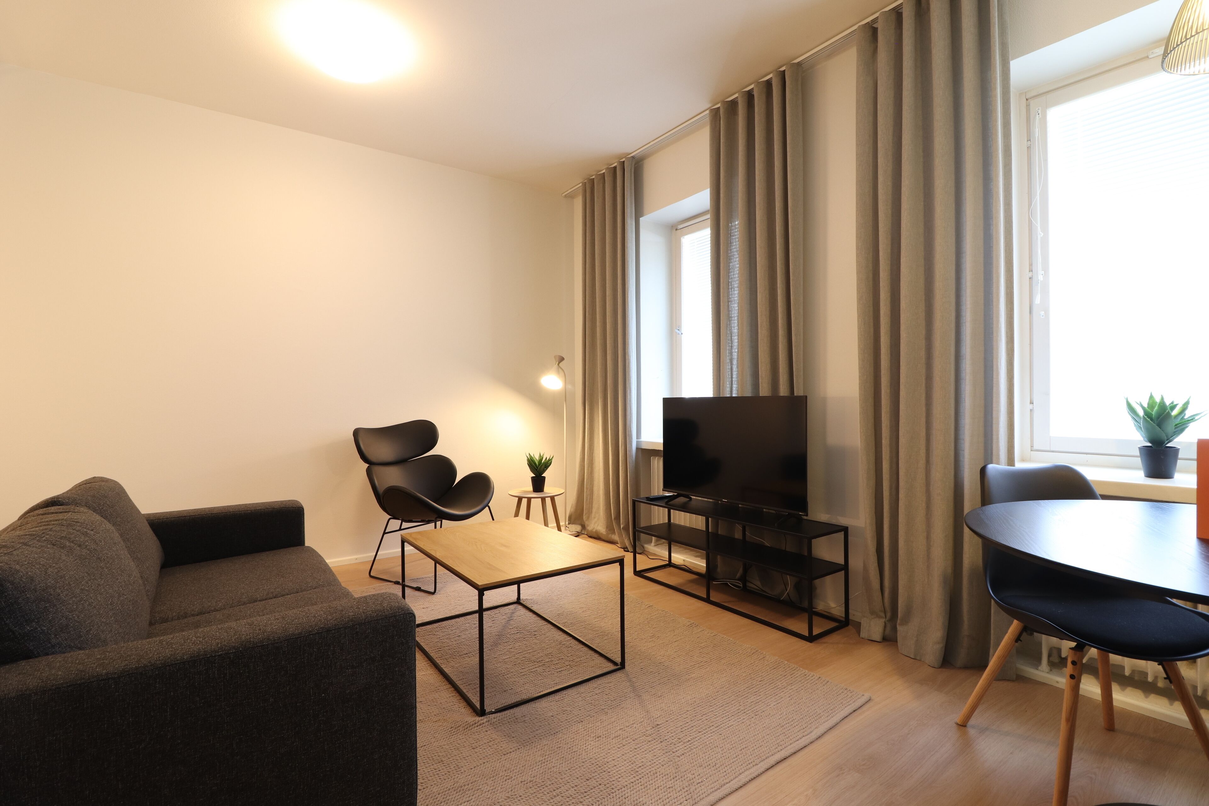 Un salon moderne comprenant un canapé, une table basse, un téléviseur et une table à manger.