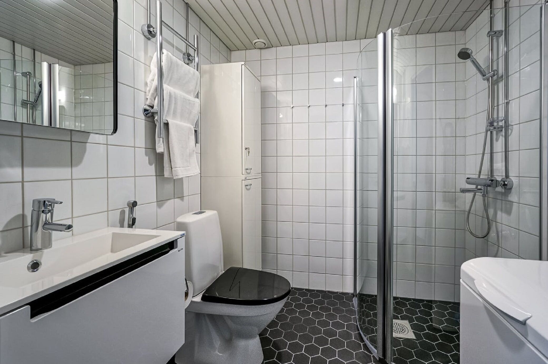 A modern bathroom with a white sink, toilet, and shower.