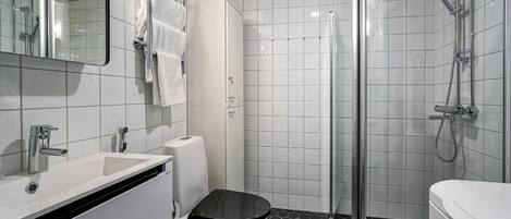 A modern bathroom with a white sink, toilet, and shower.