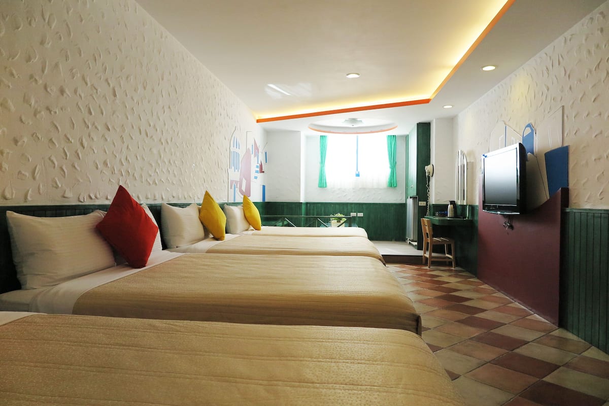 Habitación de hotel con dos camas, un televisor y una pequeña cocina.