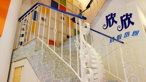 Una escalera con barandillas blancas y una pared colorida con caracteres chinos.