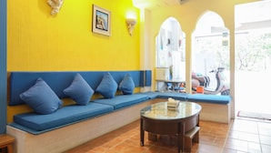 Una pared de color amarillo brillante, asientos azules y una mesa de vidrio en una habitación.
