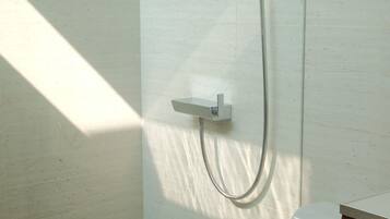 Une douche équipée d’un pommeau de douche mobile fixé au mur.