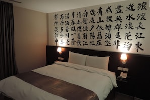 A hotel room with a large bed, two bedside lamps, and a wall with Chinese characters. - Travel Art Inn (Chiayi City)