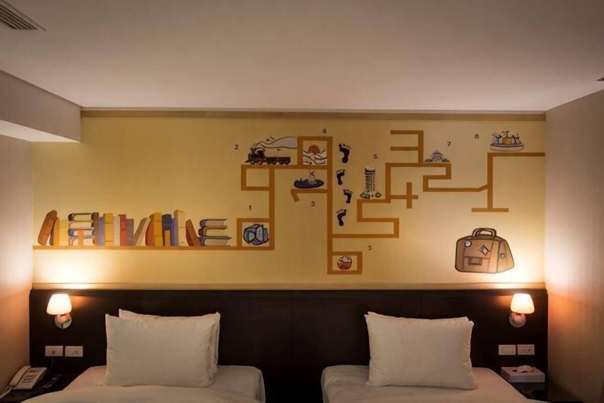 A hotel room with two beds, a maze-like wall decoration, and a nightstand with a lamp.