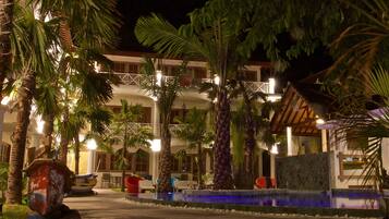 Un resort con piscina, palmeras y un edificio con balcones.