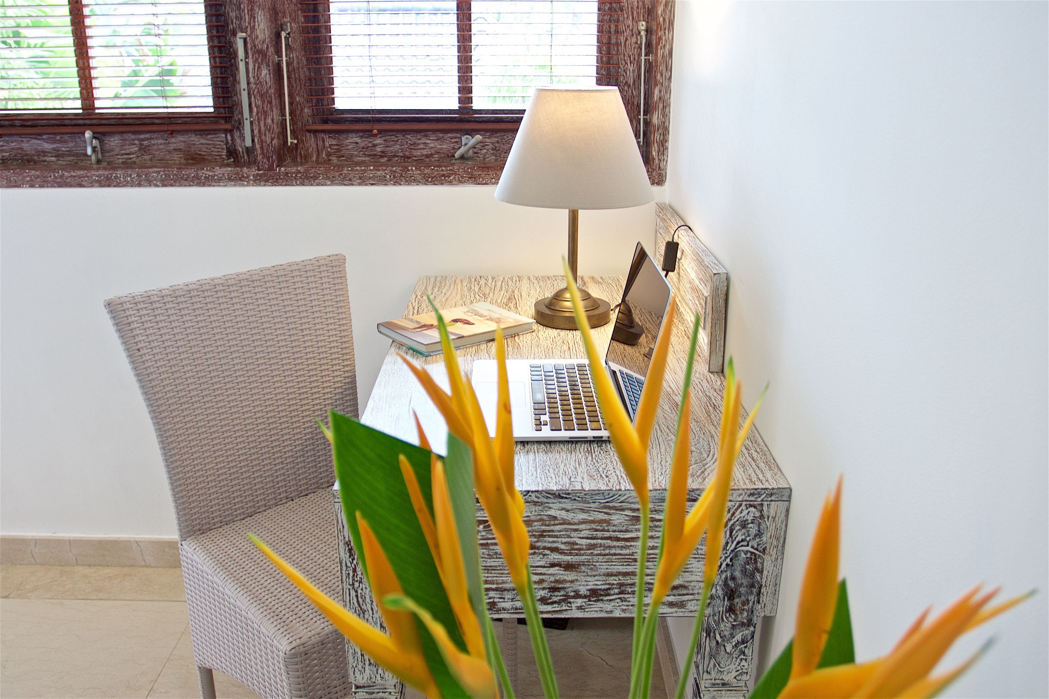 Una habitación con un escritorio de madera, una computadora portátil, una lámpara y una silla.