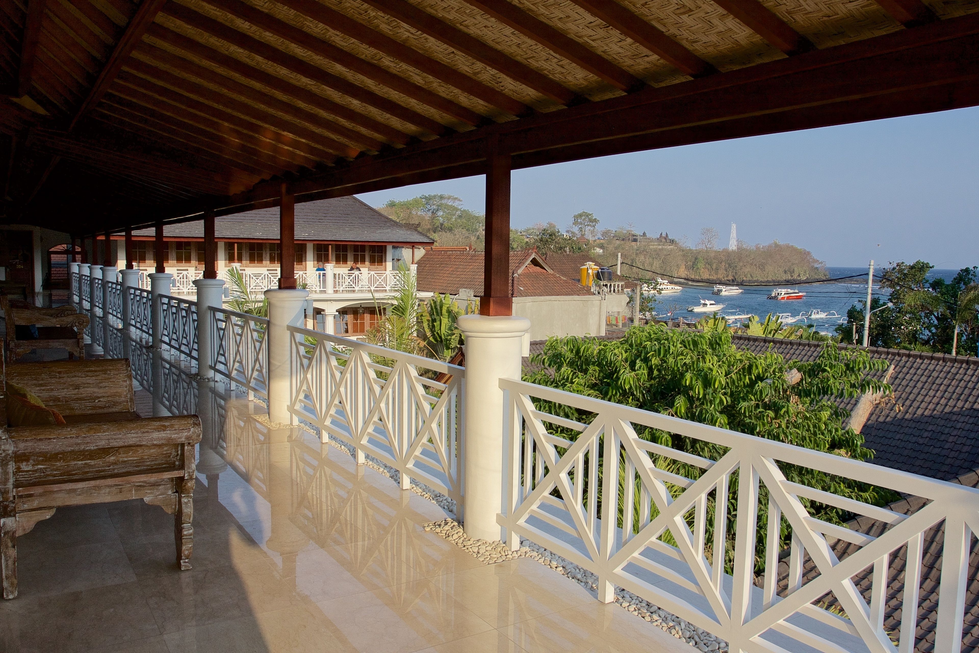 A covered balcony with a view of the sea and boats.
