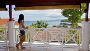 A woman standing on a balcony with a view of the sea and boats. - OK Divers Resort & Spa (Padangbai)