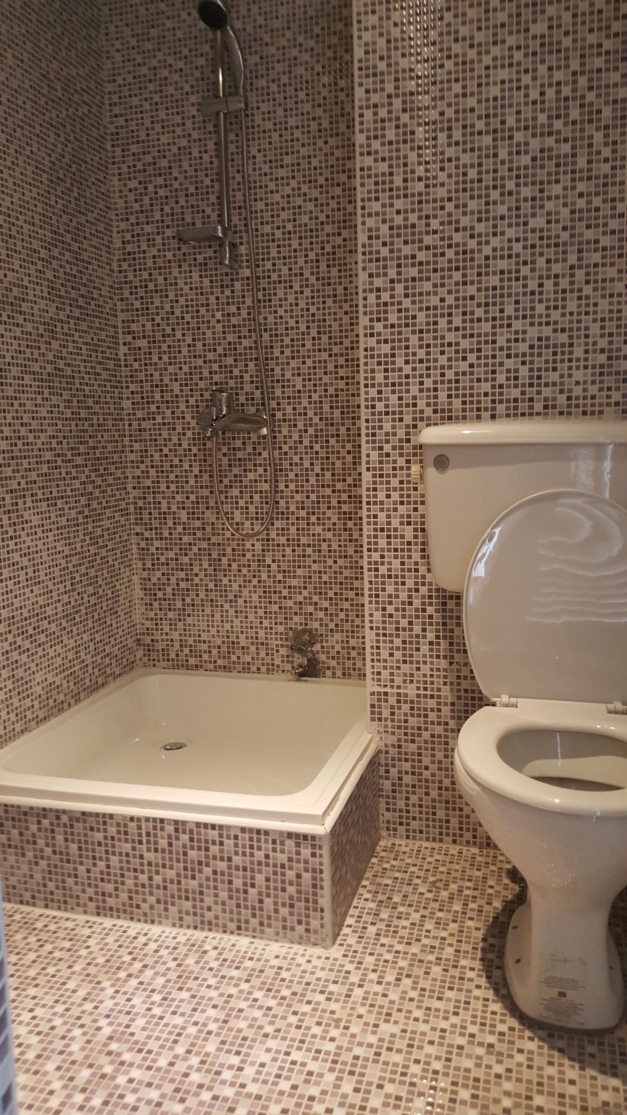 Um banheiro com piso em azulejo, banheira e vaso sanitário.