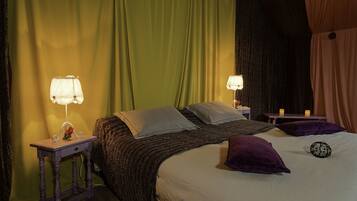 A neatly made bed with pillows, a bedside table with a lamp, and a curtain backdrop.