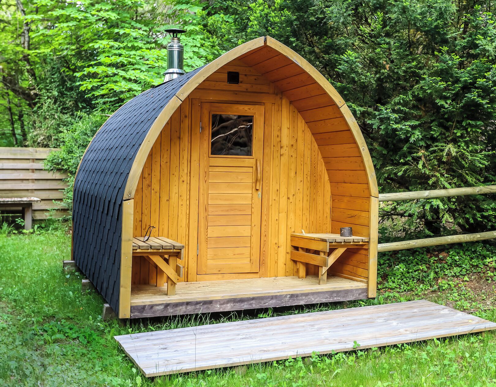 A wooden cabin with a pitched roof, a chimney, and a small porch with two benches.
