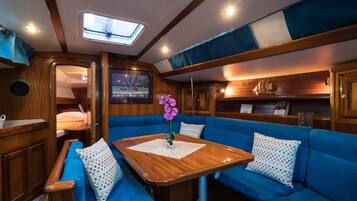 A cozy interior with a wooden table, blue cushioned seating, and a small ship model on a shelf.