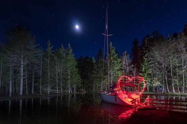 A boat docked at night with a clear view of the moon and a forested shoreline. - La Font Vineuse (Saint-Pierre-d'Argencon)
