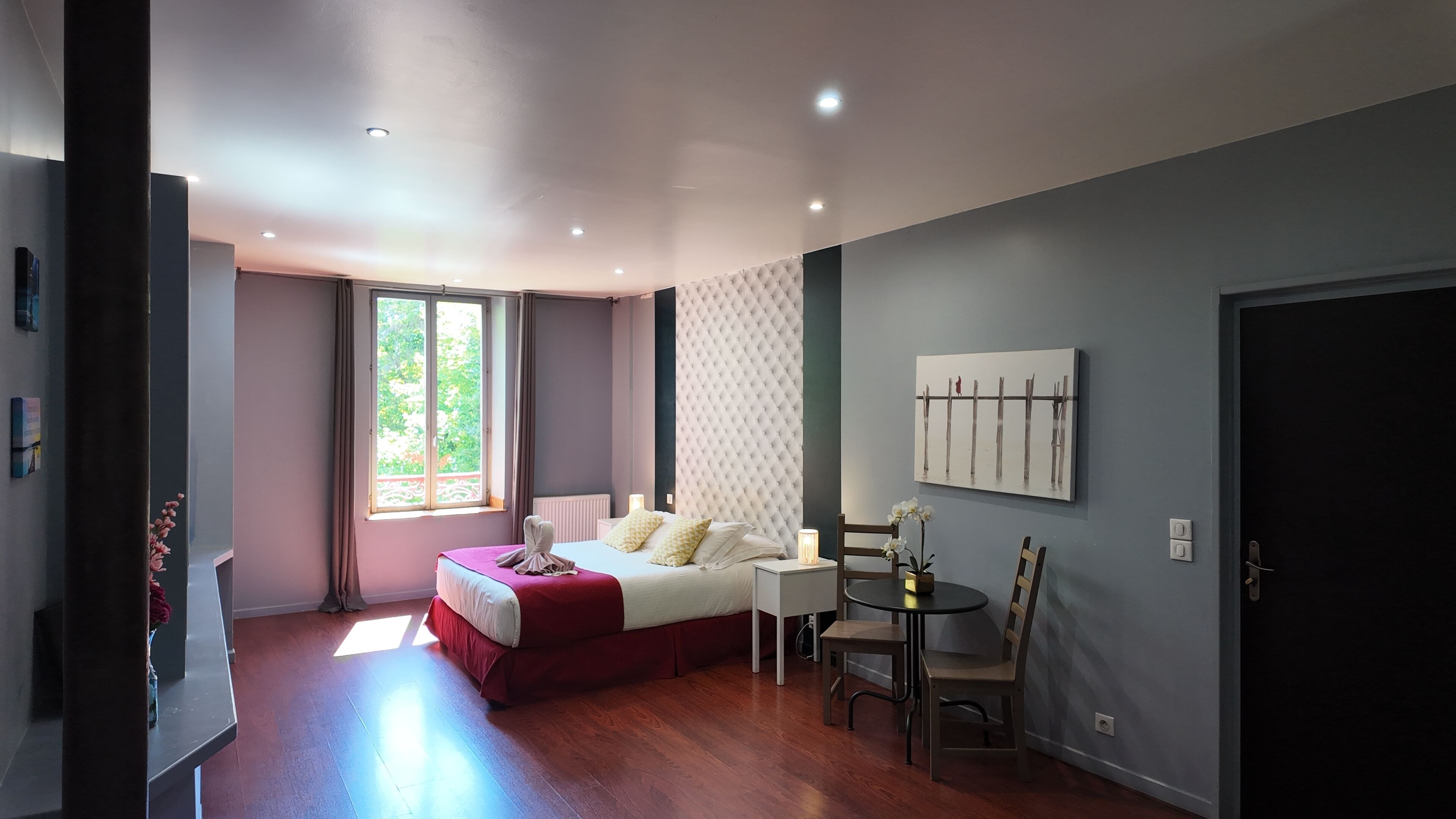 Un dormitorio moderno con cama, mesita de noche y un pequeño comedor con mesa y sillas.
