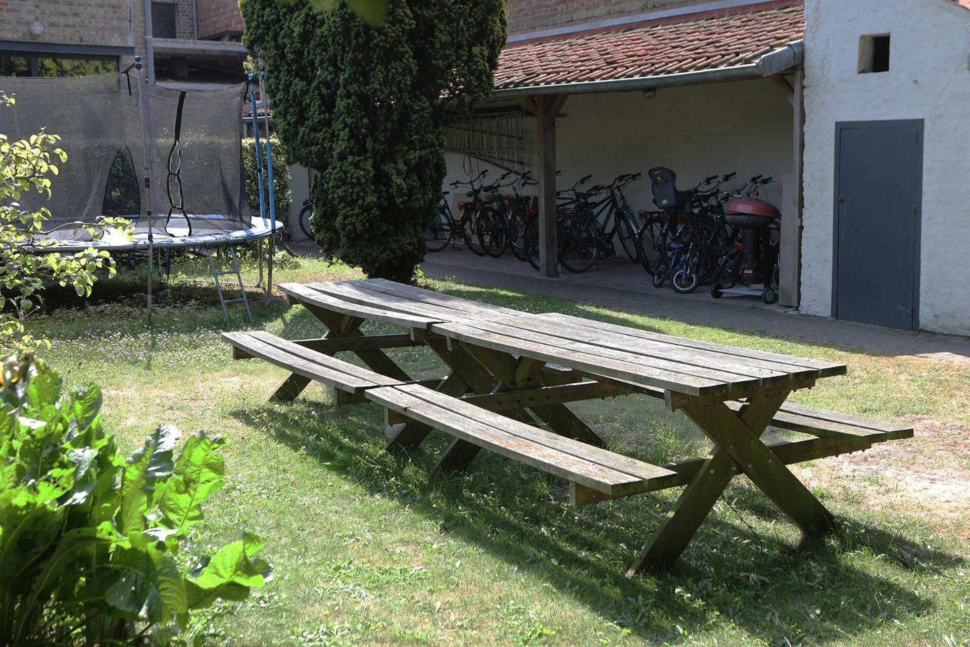 Una mesa de picnic en un área verde, con bicicletas estacionadas al fondo.