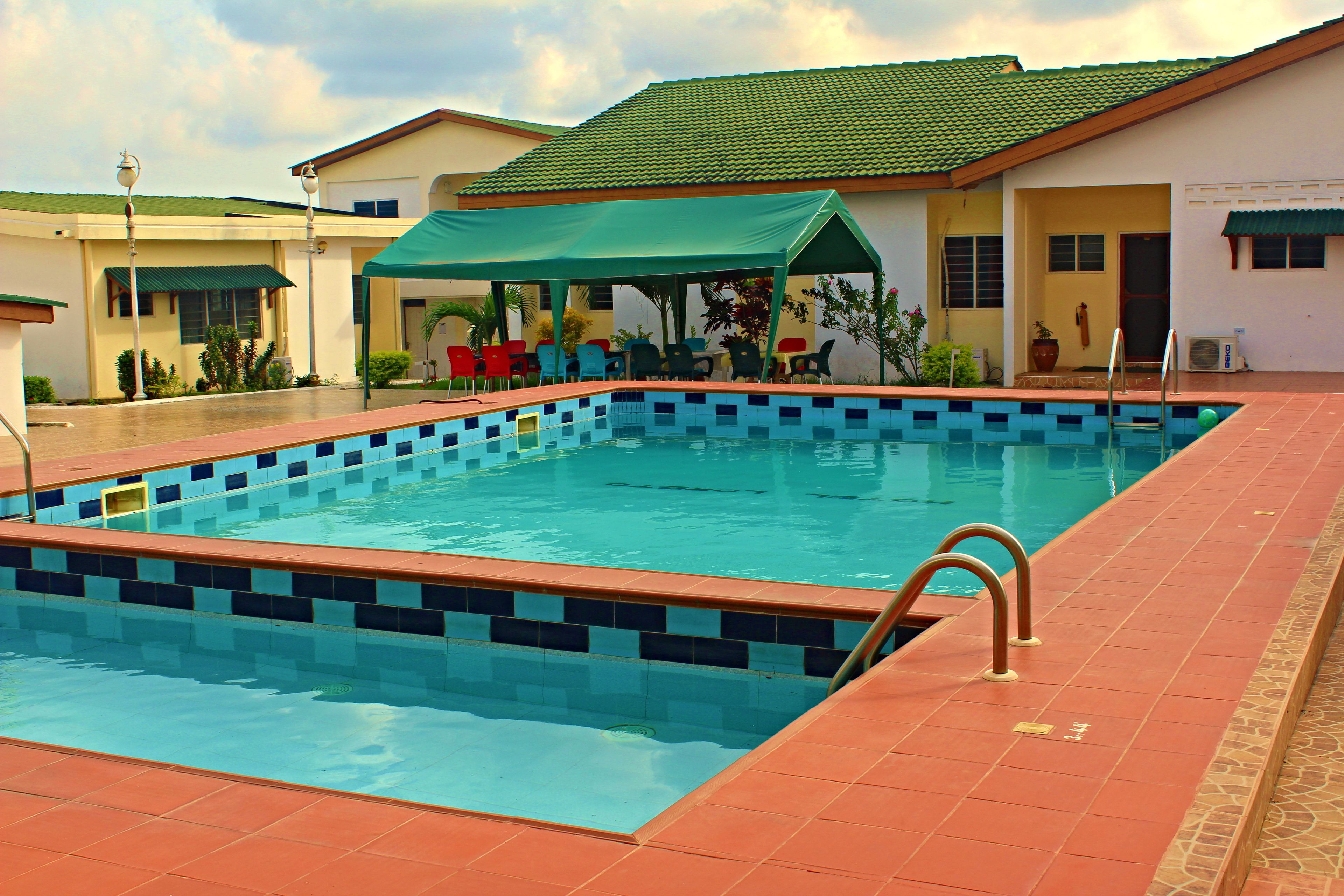 Ein rechteckiger Swimmingpool mit blau-weißen Fliesen, umgeben von einem rot gefliesten Sonnendeck.