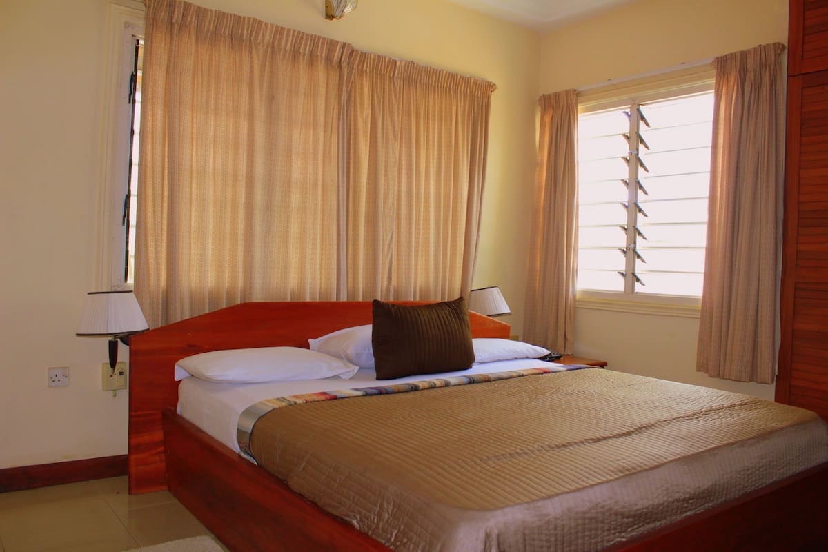 A hotel room with a large bed, two bedside lamps, and curtains on the windows.
