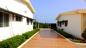 A pathway leading to a building with a tiled floor and a white exterior. - Hotel Loreto (Cape Coast)