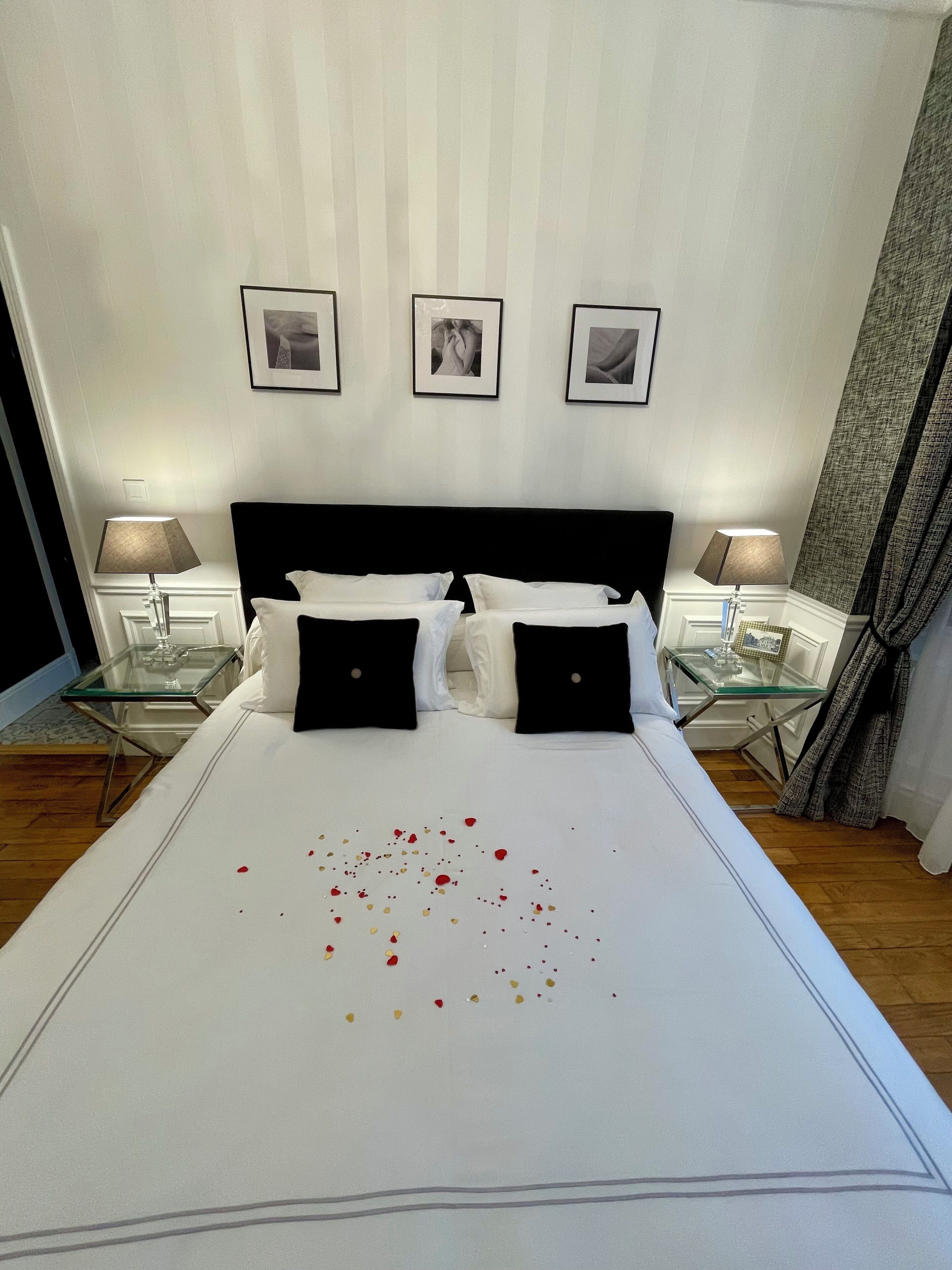 A hotel room with a large bed, two bedside tables, and three framed pictures on the wall.