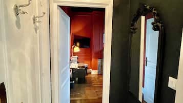 Un pasillo con piso estampado, una cabeza de ciervo montada y un espejo en la pared.