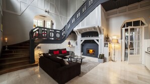 A spacious living area with a staircase, a fireplace, and a sofa. - Le Château - Fresnoy en Gohelle (Fresnoy-en-Gohelle)