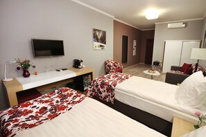 A hotel room with two beds, a desk with a computer, a TV, and a small table with a fruit bowl. - City Park Hotel (Chisinau)