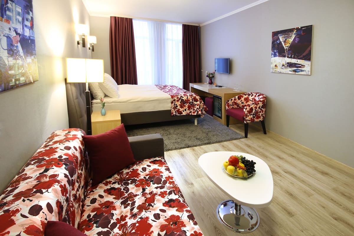 Une chambre d’hôtel équipée d’un lit, d’un bureau, d’un canapé, d’une télévision et d’un panier de fruits.