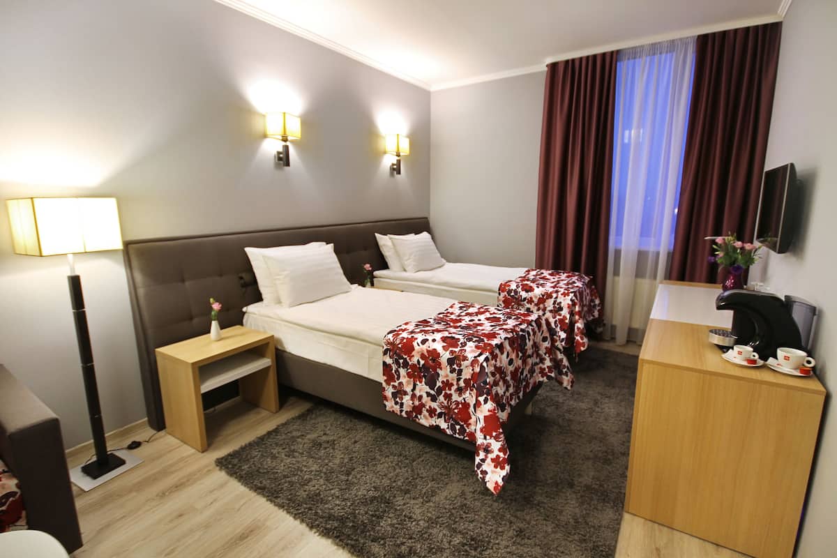 Une chambre d’hôtel avec deux lits, un bureau, une télévision et une lampe.