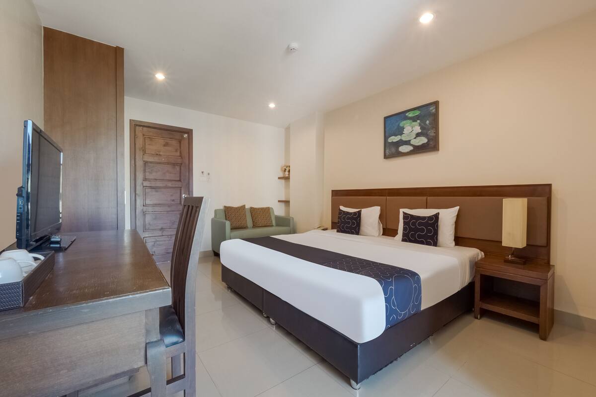 Une chambre d’hôtel avec un lit, un bureau et une chaise, une télévision et un tableau au mur.