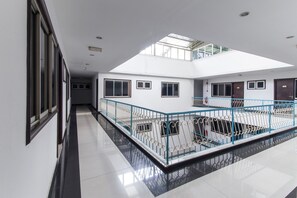 A spacious indoor area with a high ceiling, a skylight, and a central open space with a blue railing.