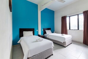 Una habitación de hotel con dos camas, una ventana con cortinas y una pared de acento azul.