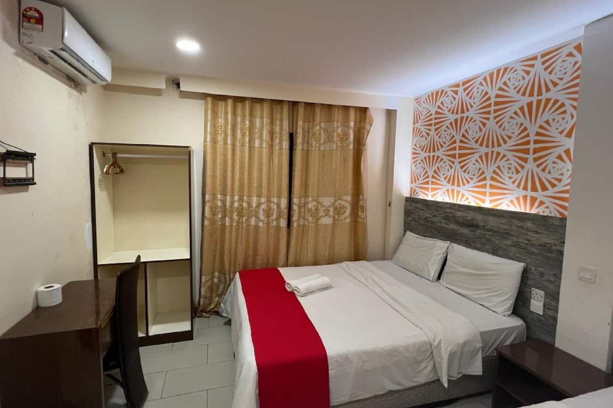 A hotel room with a bed, a wardrobe, a mirror, and a patterned wall decoration.