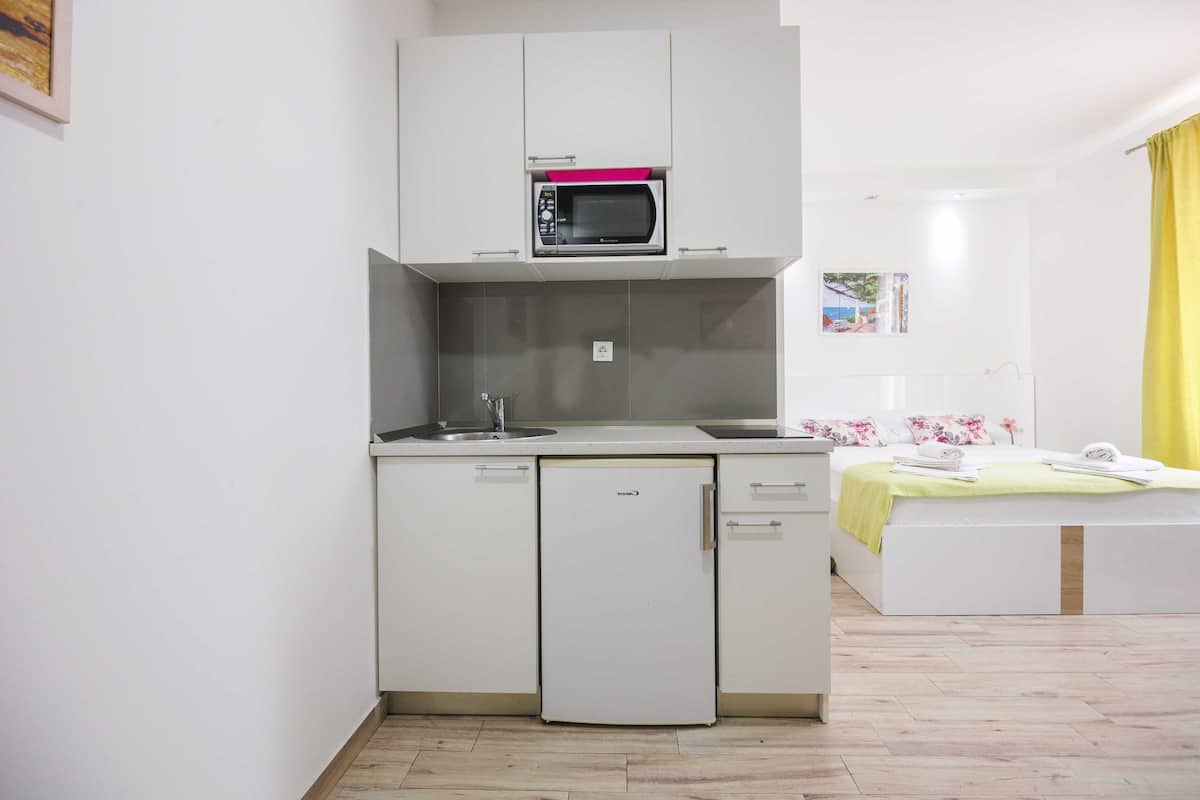 Una kitchenette compacta con microondas, un refrigerador pequeño y un lavamanos.
