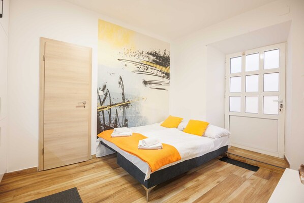 A bedroom with a bed, a painting, a door, and a window. - Apartments Gabrieri (Dubrovnik)