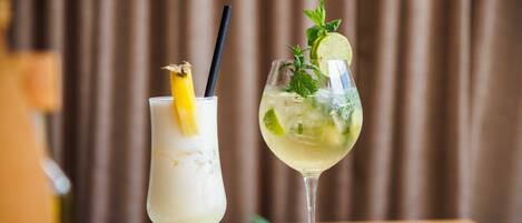 Two cocktails on a table with a plant and a blue napkin.