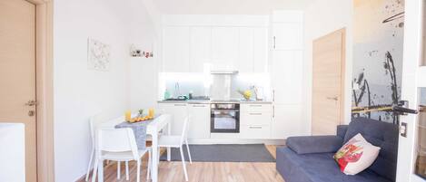 Un espacio habitable compacto con kitchenette, comedor y zona de estar.