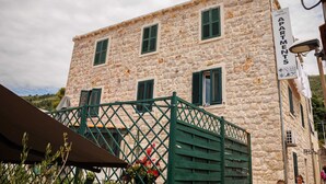 Un bâtiment en pierre doté de nombreuses fenêtres et d’un portail vert.