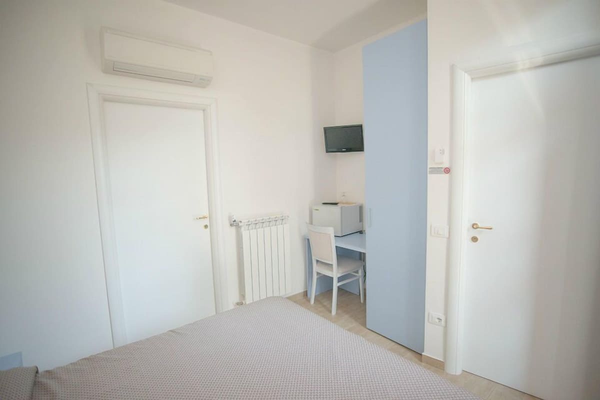 Ein Schlafzimmer mit einem Bett, einem Schreibtisch und einem Fernseher.