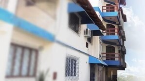 Un edificio de varios pisos con balcones y el sol brillando al fondo.