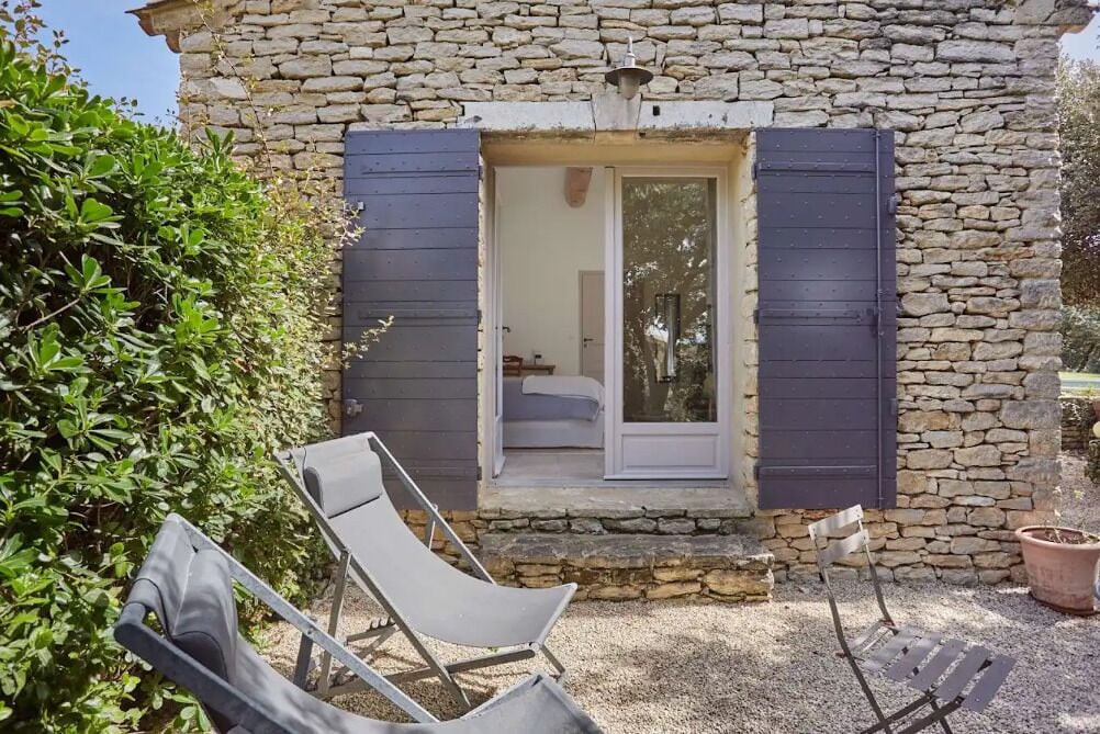 A stone building with a small entrance and two lounge chairs outside.
