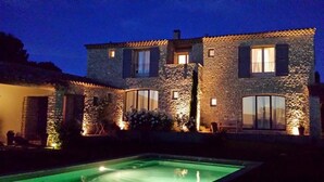 Um edifício de pedra com uma piscina ao anoitecer.