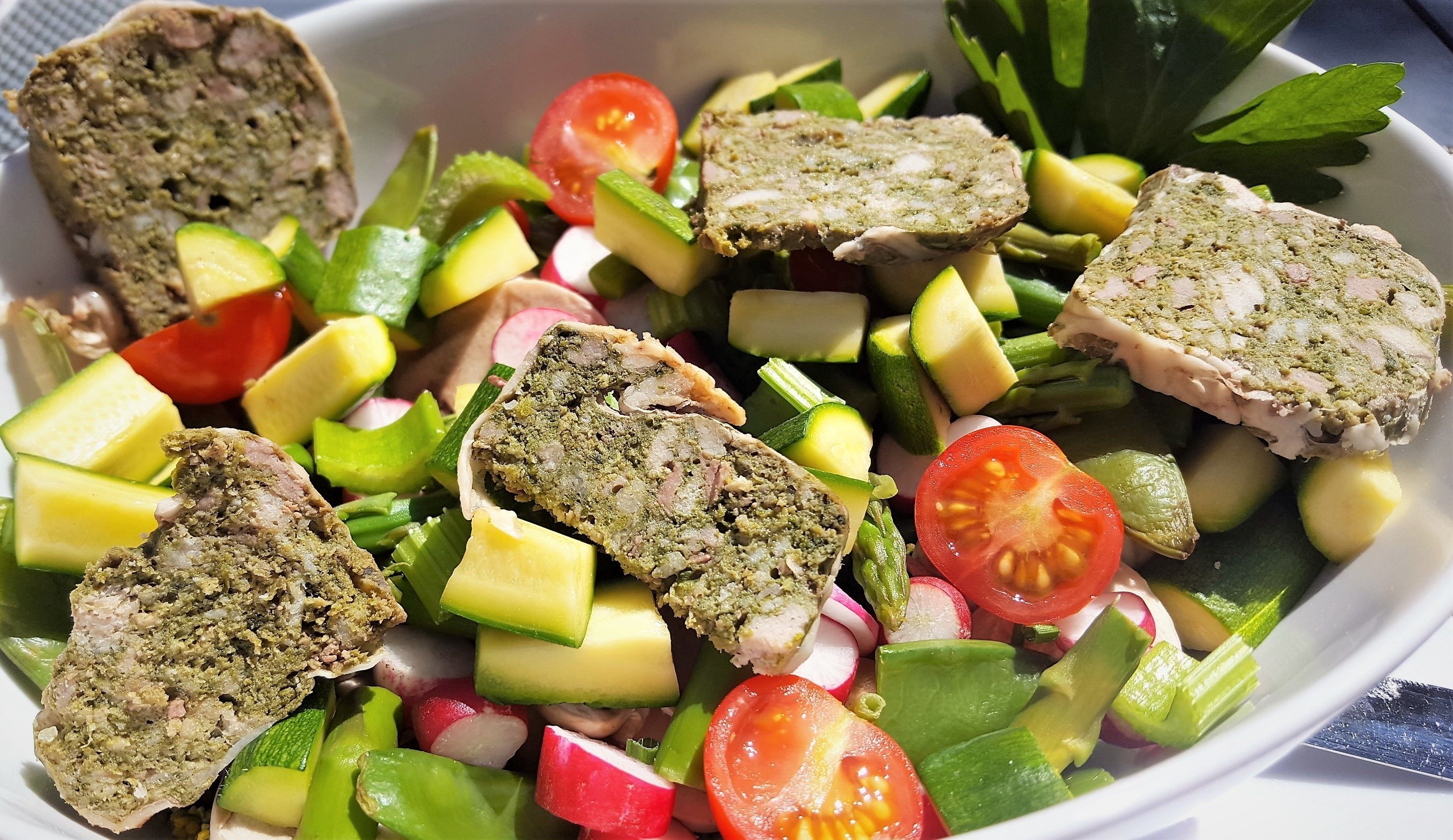A salad with various vegetables and meat roulades.