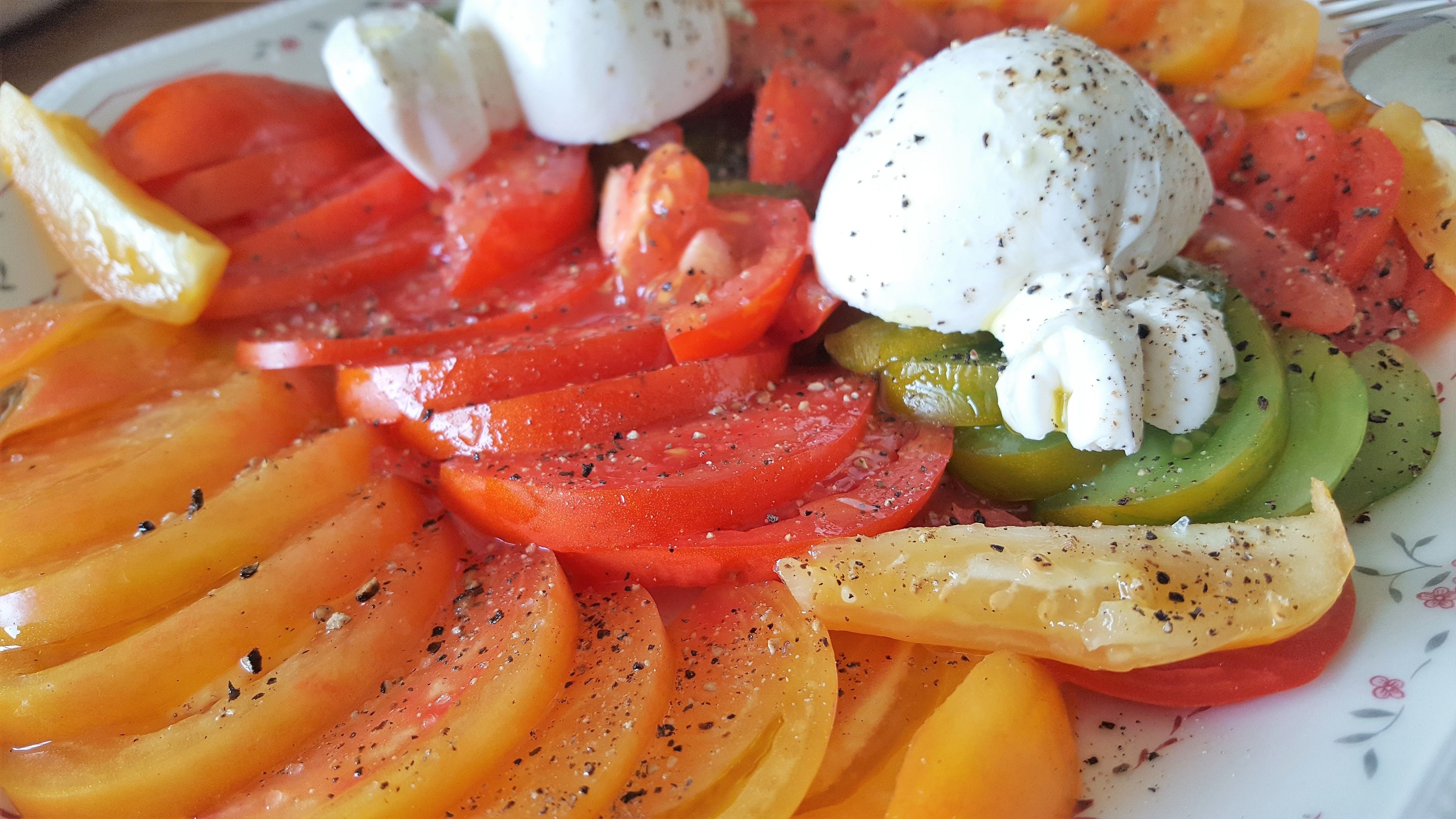 A close-up of a salad with tomatoes, green peppers, and mozzarella balls.
