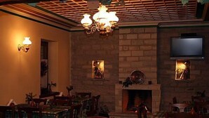 A dining area with a brick fireplace, wooden tables, and chairs. There are plates of food on the tables.