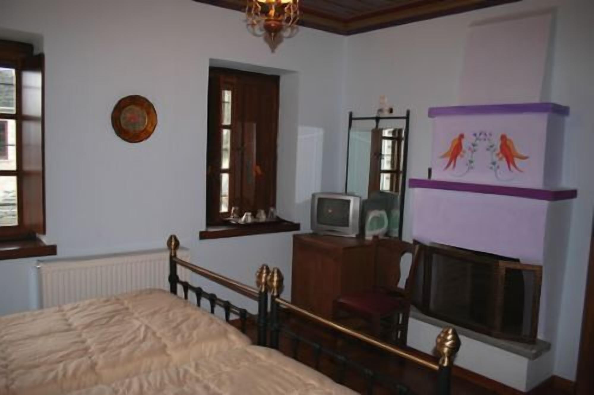 A bedroom with a bed, a dresser, a television, and a fireplace.