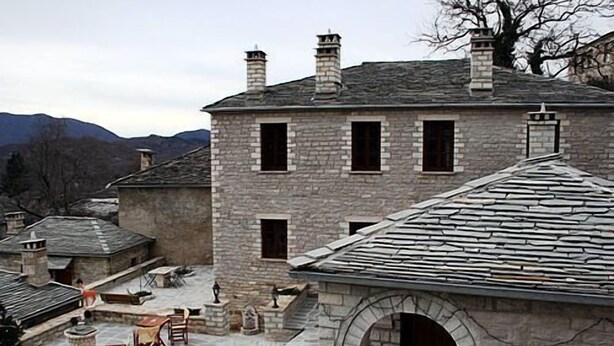 A stone building with a courtyard, featuring outdoor seating and a stone archway.