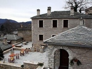 A stone building with a courtyard, featuring outdoor seating and a stone archway. - Nikolas Guesthouse (Zagori)