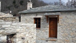 A stone building with a wooden door and window, featuring a stone staircase leading to the entrance.